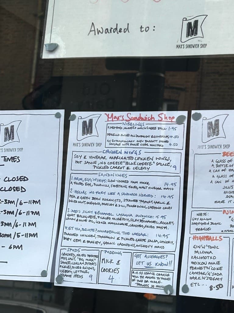 Handwritten menus taped to the window at Max’s Sandwich Shop